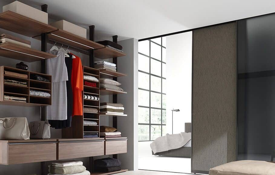 Begehbarer und beleuchteter Kleiderschrank von Ars Nova Collection Centric in Nussbaum mit Schiebetür – Blick ins angrenzende Schlafzimmer.