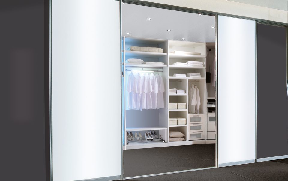 Begehbarer Kleiderschrank von Geha Möbel mit Raumteilertüren aus lichtdurchflutetem Milchglas.